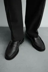 Mocasín de vestir fabricado en piel color marrón oscuro, con detalle de antifaz en el empeine, plantilla de piel y suela a contraste con ligero tacón.