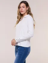Remera de silueta al cuerpo de tejido de punto acanalado blanco, con cuello polo, abertura frontal con botones dorados y mangas largas con puños abotonados.