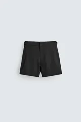 Bañador de hombre color negro, de largo medio, confeccionado en tejido técnico. Presenta cintura elástica ajustable con cordón interior, trabillas laterales, bolsillos frontales y bolsillo trasero con cierre de cremallera.