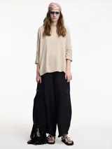 Sweater beige de mangas 3/4, con fit amplio y largo más pronunciado en la parte trasera.