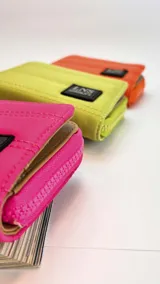 Billetera corta de diseño acolchado con cierre perimetral y solapa frontal. Incluye compartimentos internos para tarjetas y billetes, y cuenta con una correa de mano desmontable.