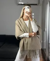 Poncho de tejido suave color blanco, con diseño abierto y flecos en el ruedo inferior.