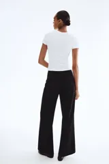 Pantalón negro de punto grueso, tiro alto con elástico oculto, botones dorados decorativos en el frente y piernas rectas de corte holgado.