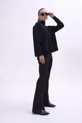 Pantalón negro de corte acampanado con aberturas en el ruedo.