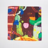 Pañuelo cuadrado de seda con estampado abstracto multicolor sobre fondo marrón.