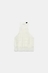 Top de cuello halter color blanco, con múltiples volantes en cascada en todo el frente y la espalda descubierta con cierre de botones y lazada en el cuello.