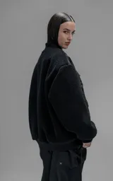 Campera estilo bomber unisex, confeccionada en una combinación de corderito sintético y paneles de ripstop. Presenta un diseño utilitario con múltiples bolsillos frontales con cierres y broches a presión, cuello, puños y ruedo en ribb elástico.