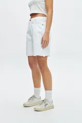 Short de jean blanco con corte a la rodilla y terminación desflecada.