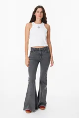 Pantalón de jean azul oscuro, corte acampanado (flare) de tiro alto, con costuras visibles en contraste y bordados tonales en la parte inferior de las piernas. El ruedo es deshilachado.