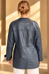 Camisa de cuero color marrón, de corte recto y largo medio, con cuello redondo a la base, cierre frontal con broches metálicos y bolsillos aplicados en los laterales.