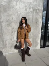 Campera de estilo bomber confeccionada en tejido tipo gamuza scuba, color marrón tostado. Presenta cierre frontal, cuello camisero, puños y ruedo elásticos, brindando un ajuste cómodo y versátil.