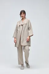 Tapado de largo medio en color arena, con cuello solapa y diseño abierto. Presenta terminaciones envivadas en tono contrastante y mangas tres cuartos.