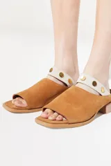 Sandalia de cuero color beige, con diseño slip on y detalle de tachas doradas.