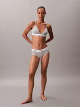 Bralette de triángulo Calvin Klein, confeccionado en una mezcla de algodón y modal. Presenta copas ligeramente forradas sin aros, tirantes ajustables y la icónica banda elástica con el logo de la marca en contraste.