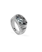 Anillo sello de metal plateado con acabado envejecido y textura rugosa. La parte superior presenta una piedra central de color celeste claro facetada, rodeada por dos estrellas superpuestas con textura. El cuerpo del anillo tiene grabados de estrellas pequeñas.