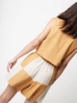 Short de lino color beige y naranja, de tiro alto con elástico en la pretina trasera, cierre delantero y botón, bolsillos delanteros y dobladillo invisible.