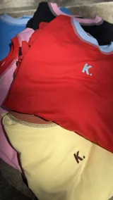 Buzo de tejido de punto color rojo, con cuello redondo y ribete celeste. Presenta costuras blancas visibles en hombros y mangas.