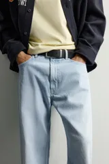 Jeans de denim de algodón en color azul con efecto desgastado, tiro medio y corte recto de ajuste holgado (loose fit). Cuenta con diseño clásico de cinco bolsillos y cierre frontal con cremallera y botón.