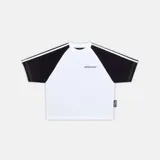 Camiseta de corte boxy fit con diseño de mangas raglán en color negro y cuerpo blanco. Presenta logo de la marca estampado en el pecho y etiqueta lateral decorativa.