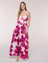 Vestido maxi de fondo blanco con estampado de flores grandes en tonos verde y marrón, con escote en V, breteles finos y detalle de abertura cut-out en el centro del busto.