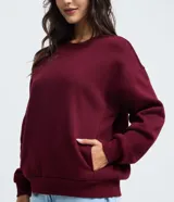 Buzo femenino de cuello redondo y manga larga, confeccionado en tejido de algodón con felpa. Presenta un diseño básico sin estampado, con puños y ruedo ajustados en tejido rib.