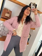 Saco tejido color rosa con textura trenzada, corte relajado, bolsillos frontales y mangas largas.
