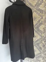 Tapado de corte recto en paño de lana color chocolate, con solapas clásicas, cierre frontal de dos botones y bolsillos laterales con solapa. Presenta un diseño estructurado con mini hombreras y acabado semi forrado.