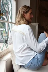 Camisa de fibrana blanca con cuello clásico, cierre frontal de botones y mangas largas con puños abotonados. Presenta un diseño minimalista y versátil.