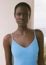 Traje de baño enterizo color celeste con textura arrugada, escote redondo y tirantes finos.