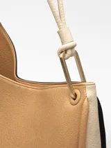 Bolso de hombro Adolfo Dominguez modelo Cumbre II, de diseño redondeado tipo media luna. Confeccionado en tejido con recubrimiento de poliuretano de textura granulada en color tostado, con detalles en blanco y asa corta tubular ajustable con pieza metálica. Incluye un compartimento principal con cierre de cremallera y bolsillo interior. Logo grabado en la parte frontal.