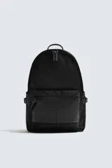 Mochila de tejido técnico en color negro, con compartimento principal con cierre de cremallera, bolsillo frontal con cierre y compartimento interior acolchado para dispositivos electrónicos. Cuenta con parte posterior acolchada, banda de sujeción para equipaje, asa de mano superior y correas de hombro ajustables.