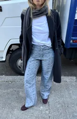 Pantalón de jean tiro alto con corte straight flare, confeccionado en algodón con estampado geométrico de rombos y motivos florales pequeños en tono gris azulado.