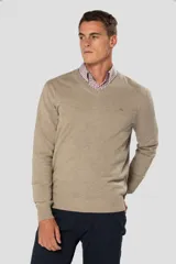 Suéter de tejido fino color beige, con cuello en V y manga larga. Presenta un pequeño logo bordado en el pecho.