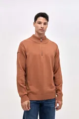 Buzo de tejido de punto color tostado, con cuello alto y cierre frontal parcial. Presenta detalles de textura acanalada en hombros y mangas, y un pequeño bordado en la manga derecha.