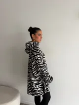 Canguro de viscosa con capucha, mangas largas abullonadas y diseño oversize con estampado animal print tipo cebra en tonos marrón y negro.