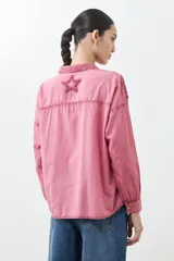 Camisa de corte clásico y manga larga en tono celeste claro, con diseño de estrellas aplicadas en tejido desflecado. Presenta cuello camisero y cierre frontal con botones.