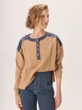 Buzo de manga larga con diseño color block. Cuerpo principal color camel, sección central de la espalda color azul marino liso y hombros con tejido de lana texturado en tonos azules. Posee un parche de cuero marrón con el logo grabado en la espalda.