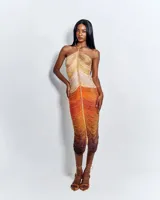 Vestido corto de crochet color marrón con acabado brillante, diseño ajustado al cuerpo, escote halter con tirantes de cadena metálica dorada y abertura frontal pronunciada.