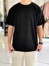 Remera negra de corte oversize con cuello redondo, mangas cortas y textura de líneas sutiles.