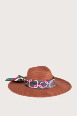 Pañuelo cuadrado con diseño estampado de cadenas y eslabones entrelazados en tonos verde, fucsia y blanco, con borde enmarcado y logo de la marca repetido en el contorno.
