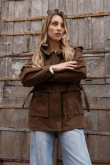 Gabardina liviana color beige con capucha, cierre frontal oculto y cintura ajustable mediante cordón. Presenta bolsillos delanteros amplios y mangas largas con puños rectos.