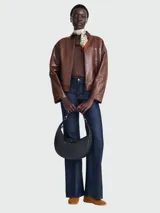 Cartera hobo Longchamp modelo Le Pliage Xtra de cuero color negro, con diseño curvilíneo tipo media luna, asa ajustable con herrajes metálicos y solapa frontal con cierre de botón a presión y logo grabado.