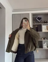Campera tipo bomber de gamuza en color tostado, con diseño holgado, mangas amplias y cierre frontal con solapa.