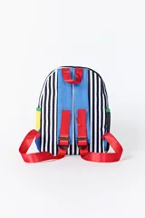 Mochila con diseño combinado que presenta un patrón de rayas verticales blancas y negras en la parte superior, un bolsillo frontal con solapa verde y cuerpo azul, y laterales en color amarillo. Incluye cierres con tiradores amarillos.
