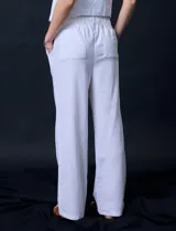 Pantalón de lino de corte recto y tiro medio, con pretina elástica ancha y lazo de ajuste frontal. Presenta bolsillos laterales verticales y bolsillos traseros.