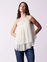 Blusa negra de gasa con breteles finos trenzados, escote redondo y capas superpuestas de encaje y gasa en el frente.