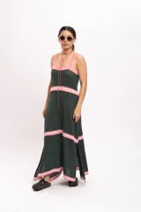 Vestido largo de punto tipo solera en color verde oscuro, con tirantes anchos y detalles de rayas horizontales en color rosado claro en el escote, la cintura, los cortes de la falda y el ruedo.