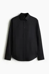 Camisa de vestir negra con cuello italiano, cierre frontal de botones y mangas largas con puños ajustables. Presenta un corte entallado y bajo redondeado.