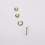 Par de aros dorados tipo argolla con incrustaciones de cristales de colores. Fabricados en acero con baño de oro de 18k y cristales Cubic Zirconia.