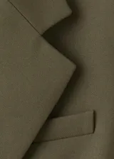 Blazer verde militar, de corte estructurado, con solapas de muesca, bolsillos con solapa y cierre frontal de un botón.